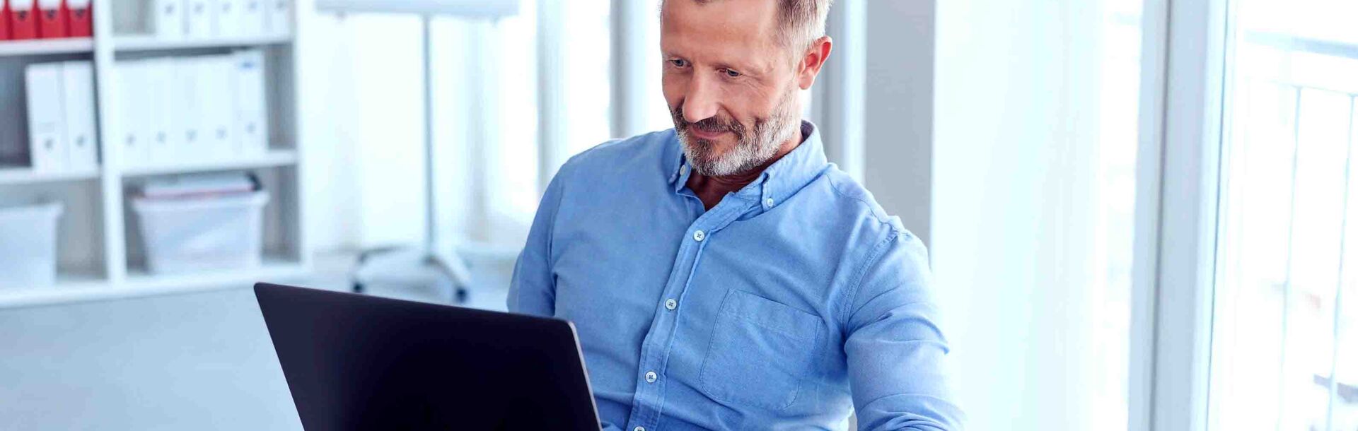 Mann sitzt vor Laptop und arbeitet am E-Learning Kommunikation