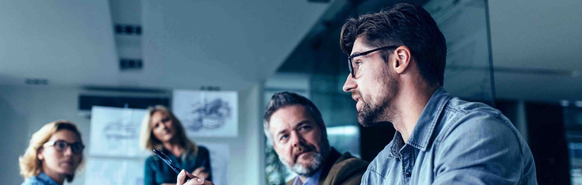 Gruppe in Meetingraum hört Mann zu beim Entscheidungen treffen